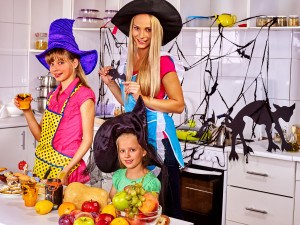 Happy family with children preparing halloween food. Children with mother preparing festive dinner on halloween holiday.