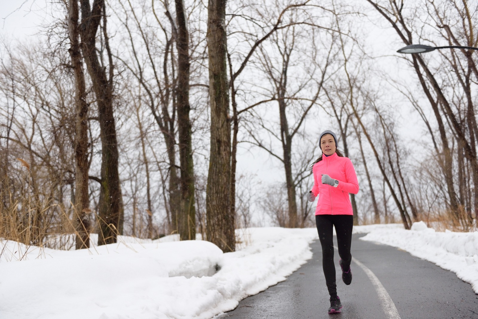 Woman jogging in snowy city park - winter fitness. Female athlet
