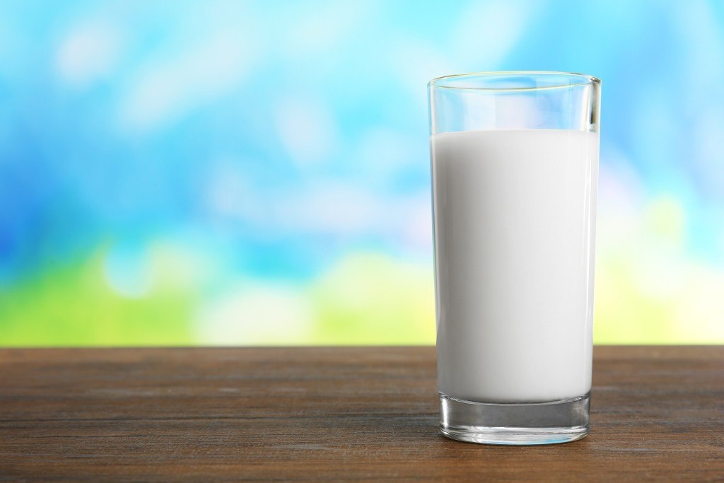 Glass of milk on table on blurred natural background