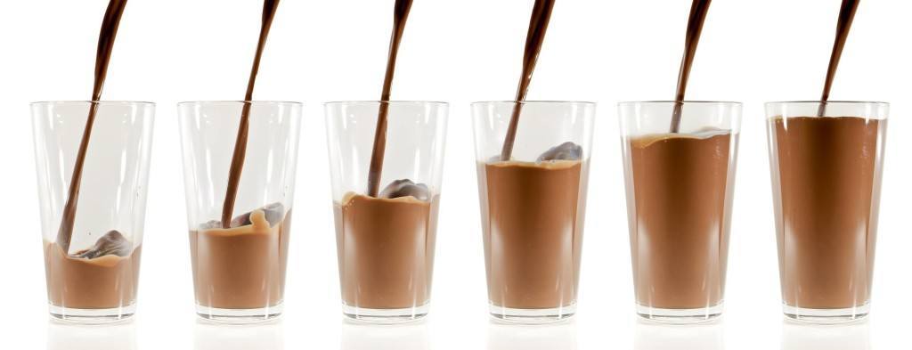 pouring chocolate milk into the glass isolated on white