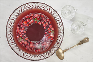 A bowl of cranberry punch with glasses on a table