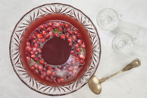 A bowl of cranberry punch with glasses on a table