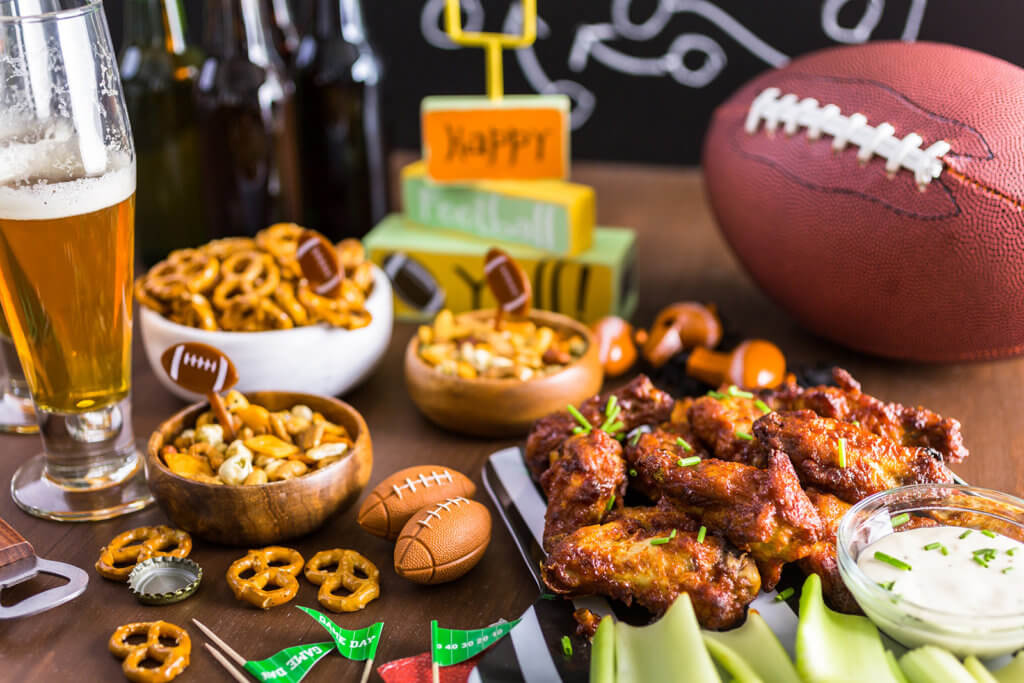 buffalo wings with assorted football game snacks on a table