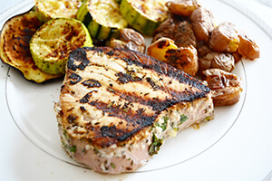 Lemon garlic tuna steaks on a plate with roasted potatoes and vegetables