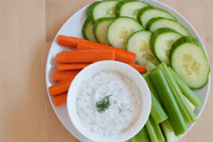 a vegetable, yogurt dill dip served with cut up cucumbers, carrots and celery